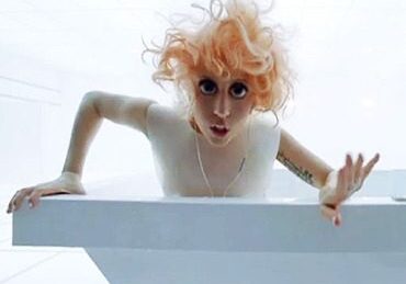 Woman in white room, wide-eyed expression