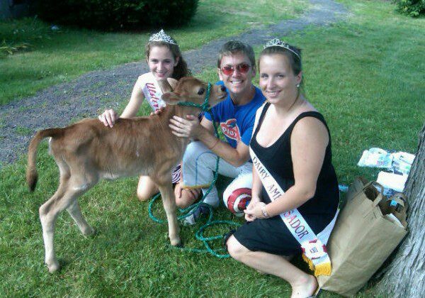 Women with calf outdoors, wearing sashes