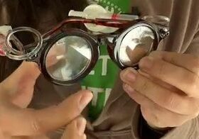 Hands holding DIY glasses with magnifying lenses.