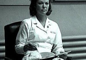 Woman in white nurse outfit, seated