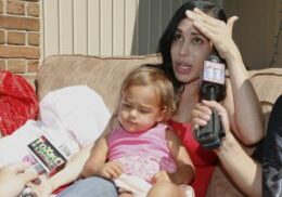 Press interviewing woman holding a toddler