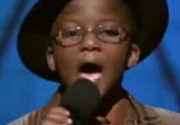 Child singing with microphone and hat