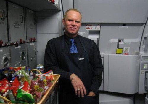 Flight attendant in airplane galley with snacks