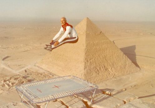 Man jumping on trampoline near pyramid
