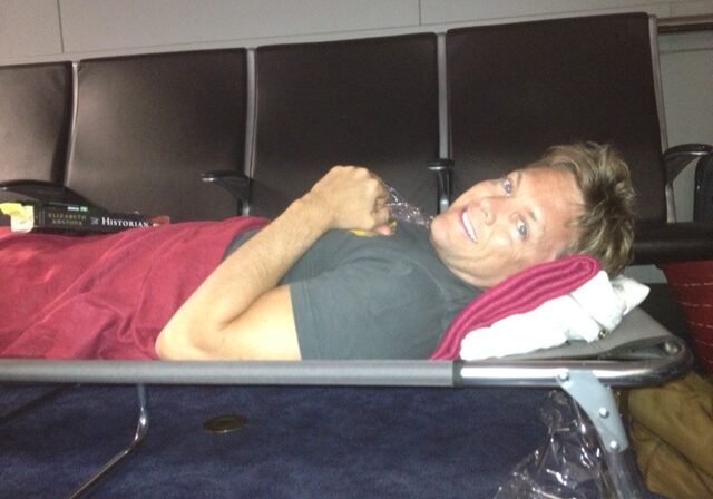 Man lying on an airport bench